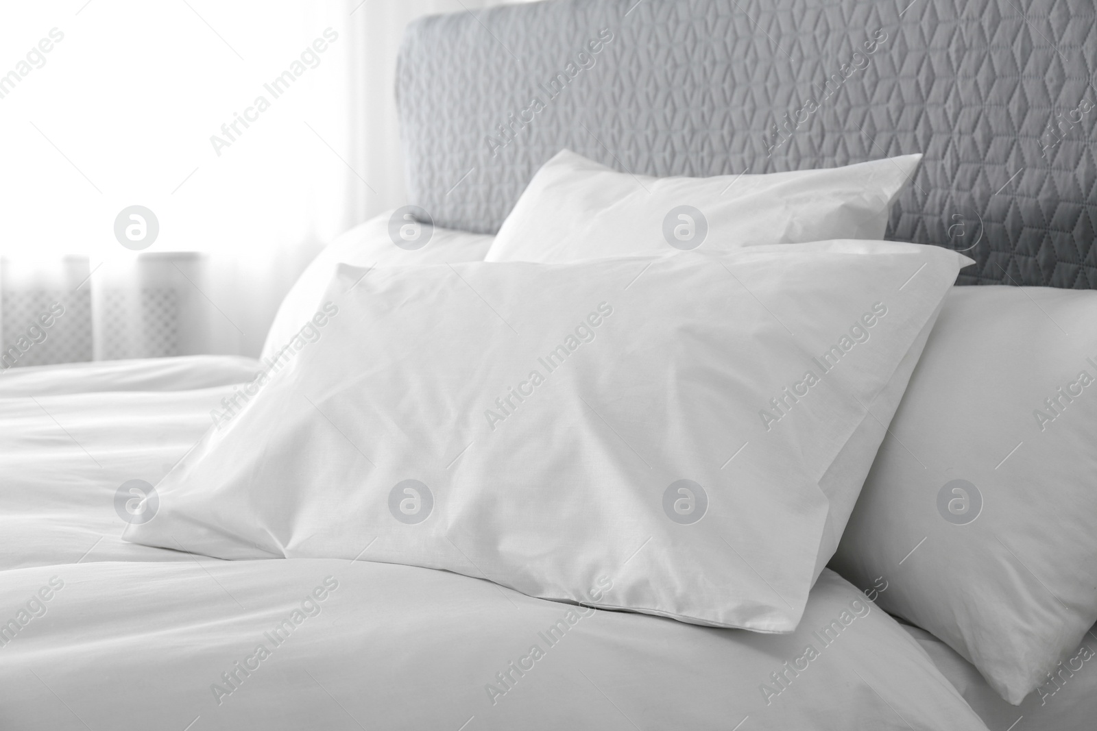 Photo of Bed with soft fluffy pillows at home