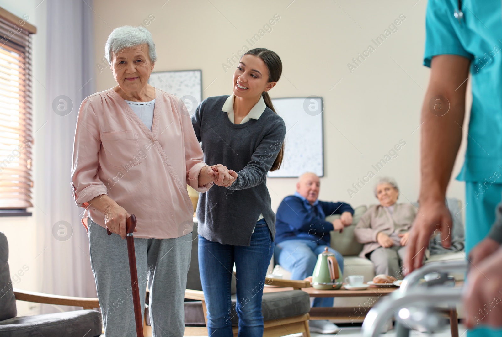 Photo of Care worker helping to elderly woman with stick in geriatric hospice