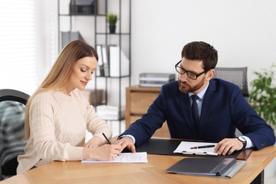 Woman signing document while having meeting with lawyer in office