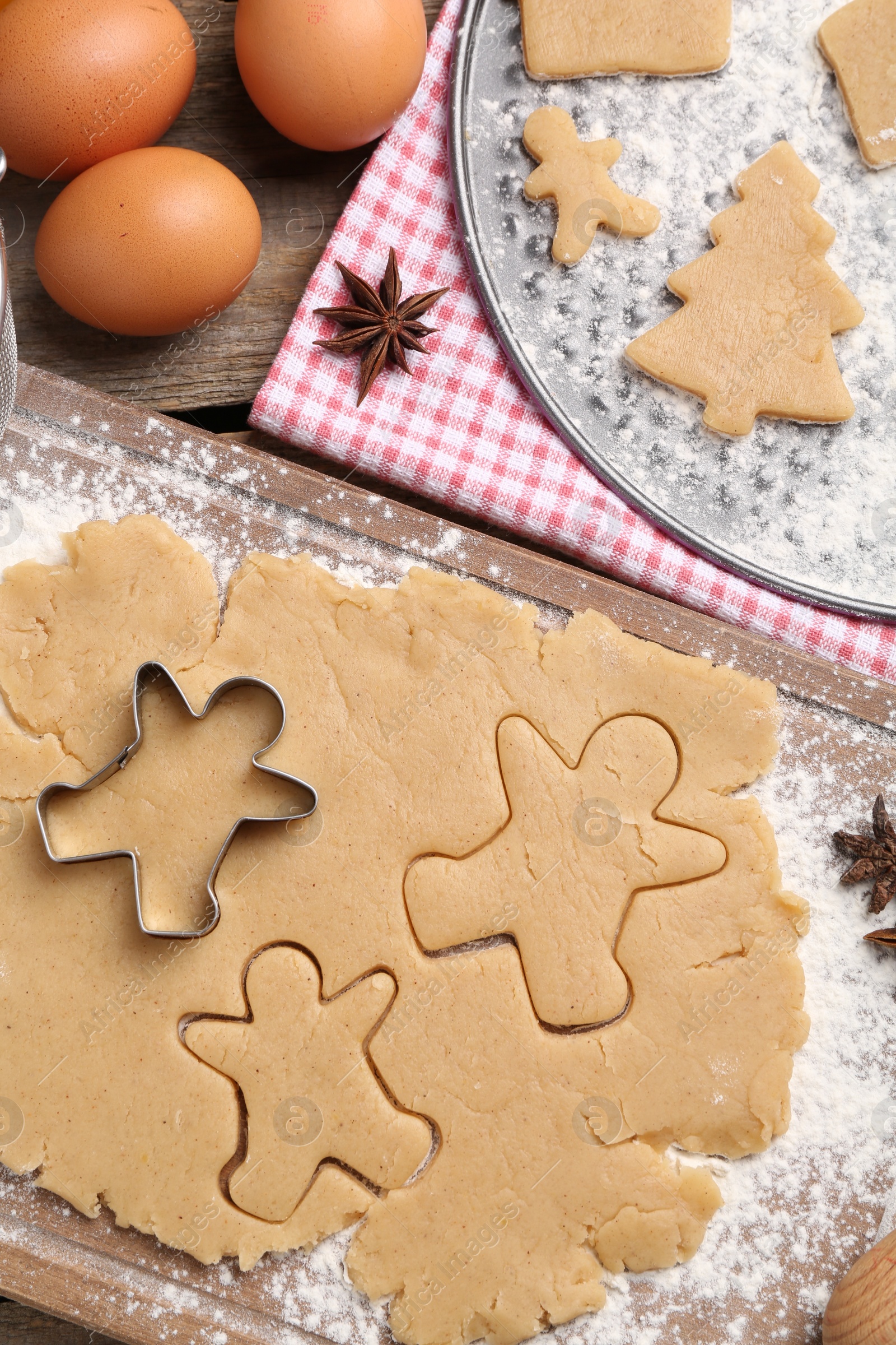 Photo of Making Christmas cookies. Flat lay composition with ingredients and raw dough on wooden table