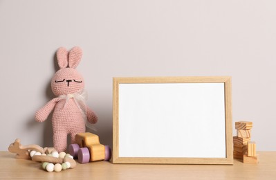 Empty square frame and different toys on wooden table