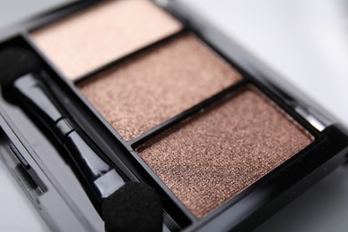 Photo of Beautiful eyeshadow palette and applicator as background, closeup. Professional cosmetic product
