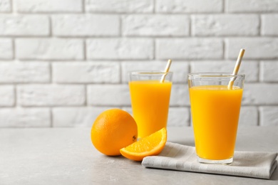 Glasses of orange juice and fresh fruits on table