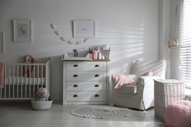 Photo of Chest of drawers with changing tray and pad in baby room. Interior design
