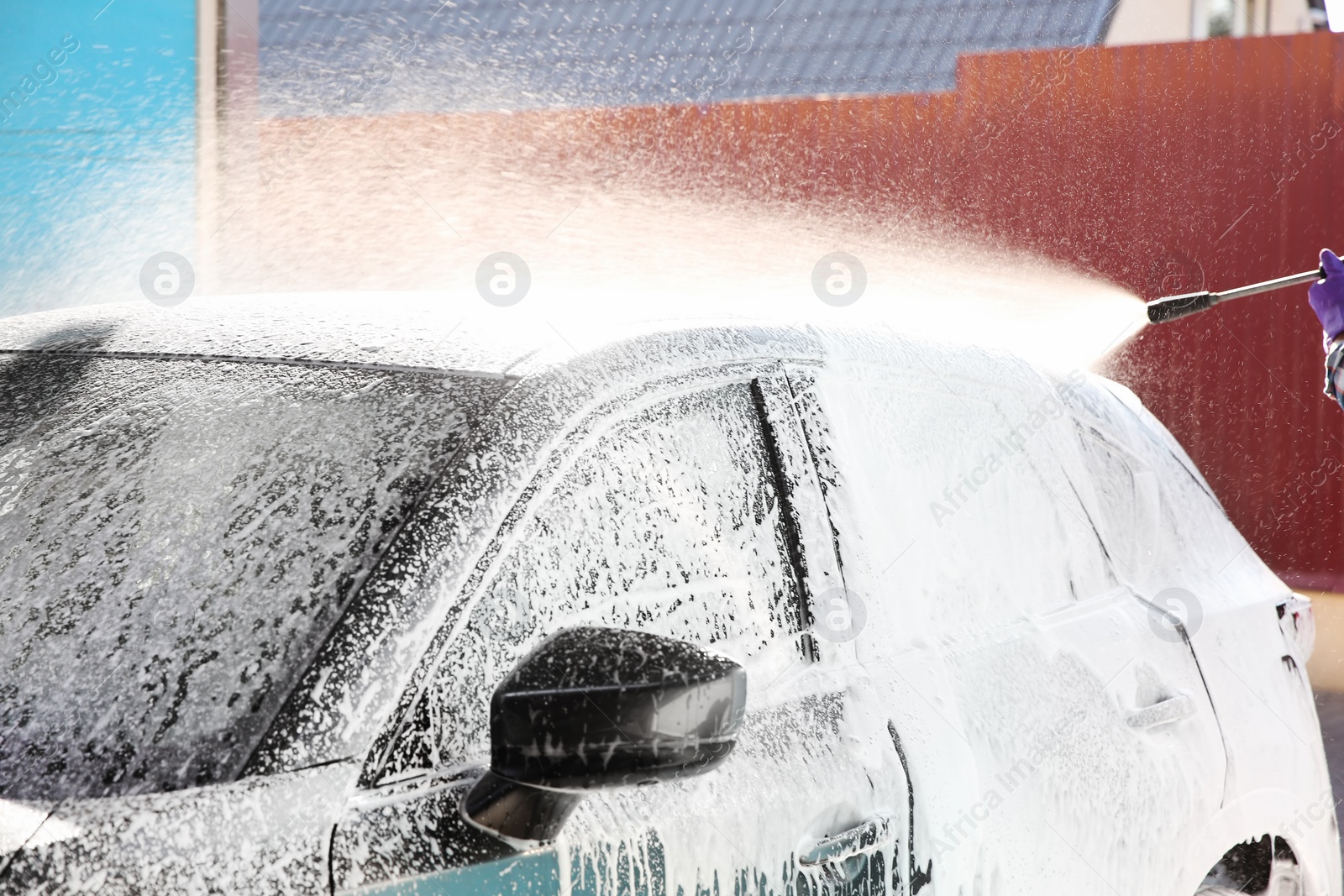 Photo of Worker cleaning automobile with high pressure water jet at car wash