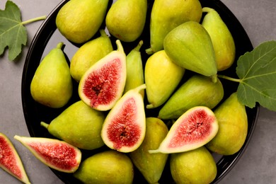 Photo of Cut and whole green figs on light gray table, top view