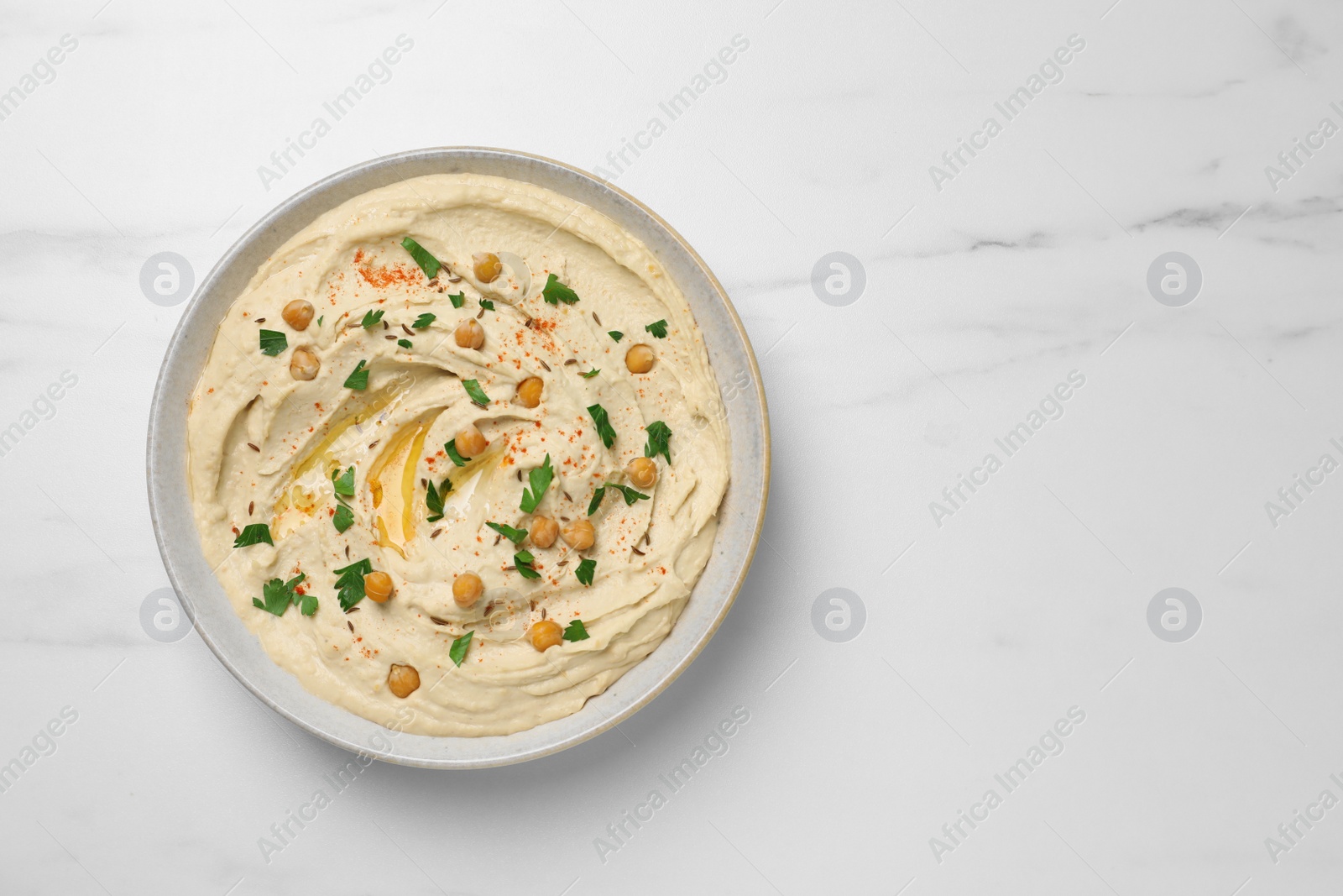 Tasty hummus with garnish in bowl on white marble table, top view. Space for text Photo of Tasty hummus with garnish in bowl on white marble table, top view. Space for text