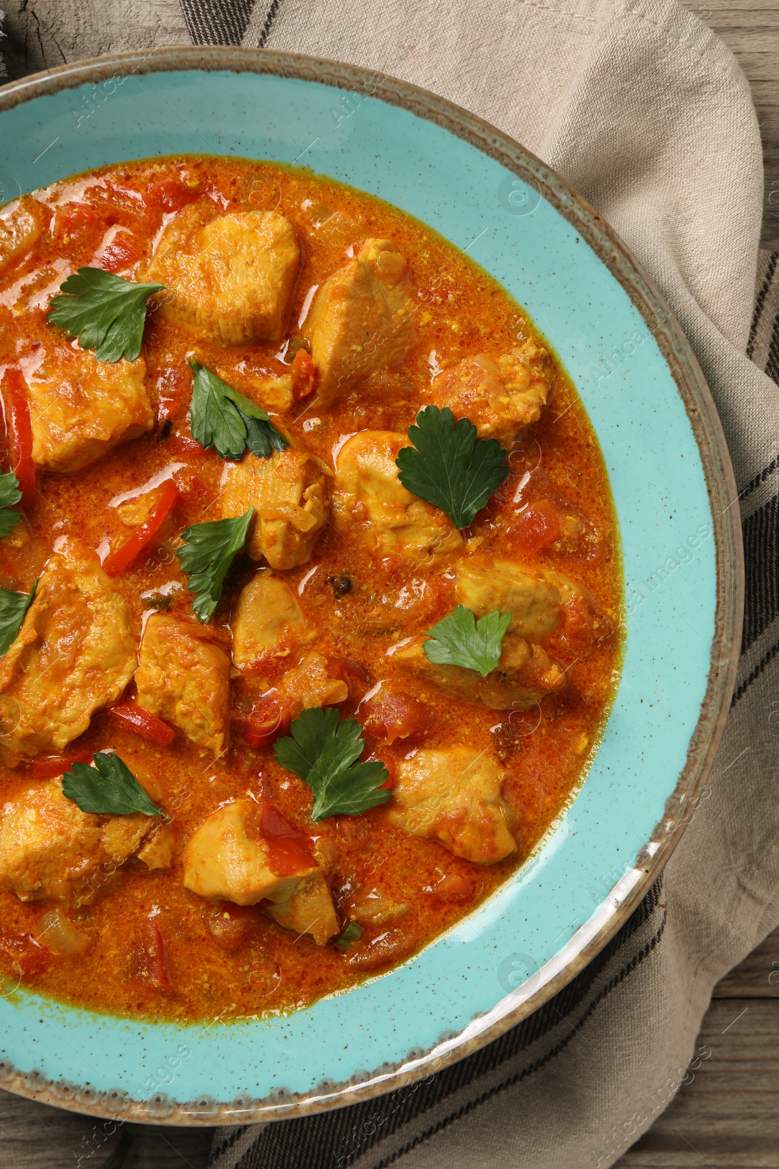 Photo of Delicious chicken curry on wooden table, top view