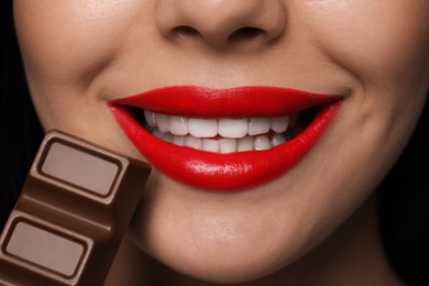 Young woman with red lips eating chocolate, closeup