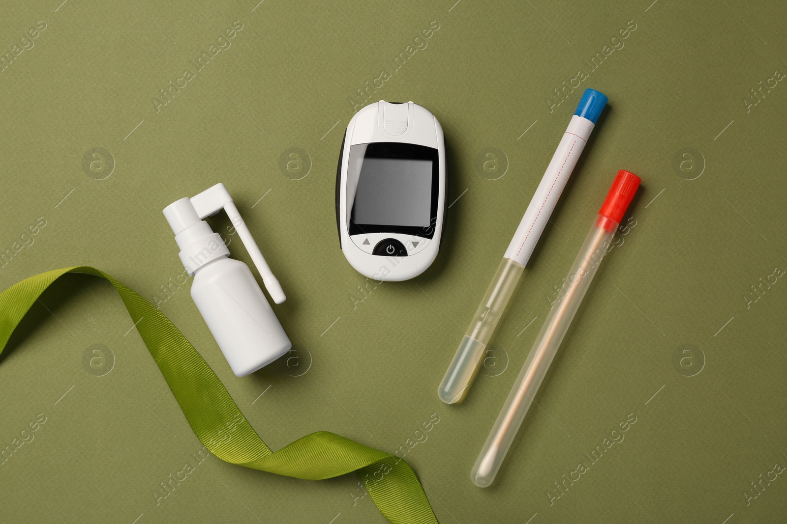 Photo of Spray bottle, sample collection kit and digital glucometer on olive background, flat lay. Medical gift