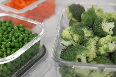 Photo of Containers with green broccoli and peas on table, closeup. Food storage
