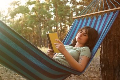 Photo of Woman with book resting in comfortable hammock outdoors