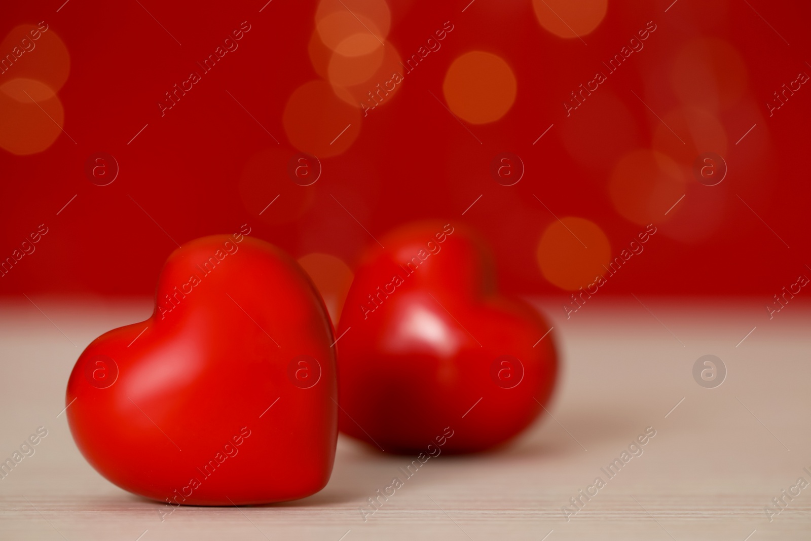 Photo of Red decorative hearts on table against red background, space for text. Valentine's Day