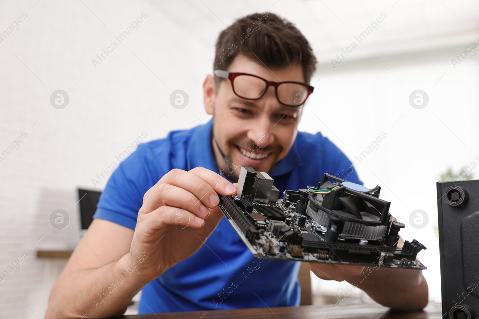 Photo of Male technician repairing computer at table indoors