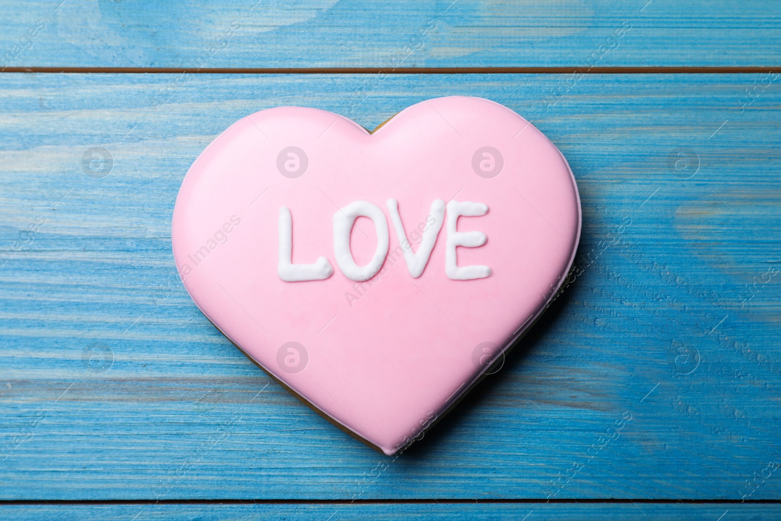 Photo of Decorated heart shaped cookie with word Love on blue wooden table, top view. Valentine's day treat