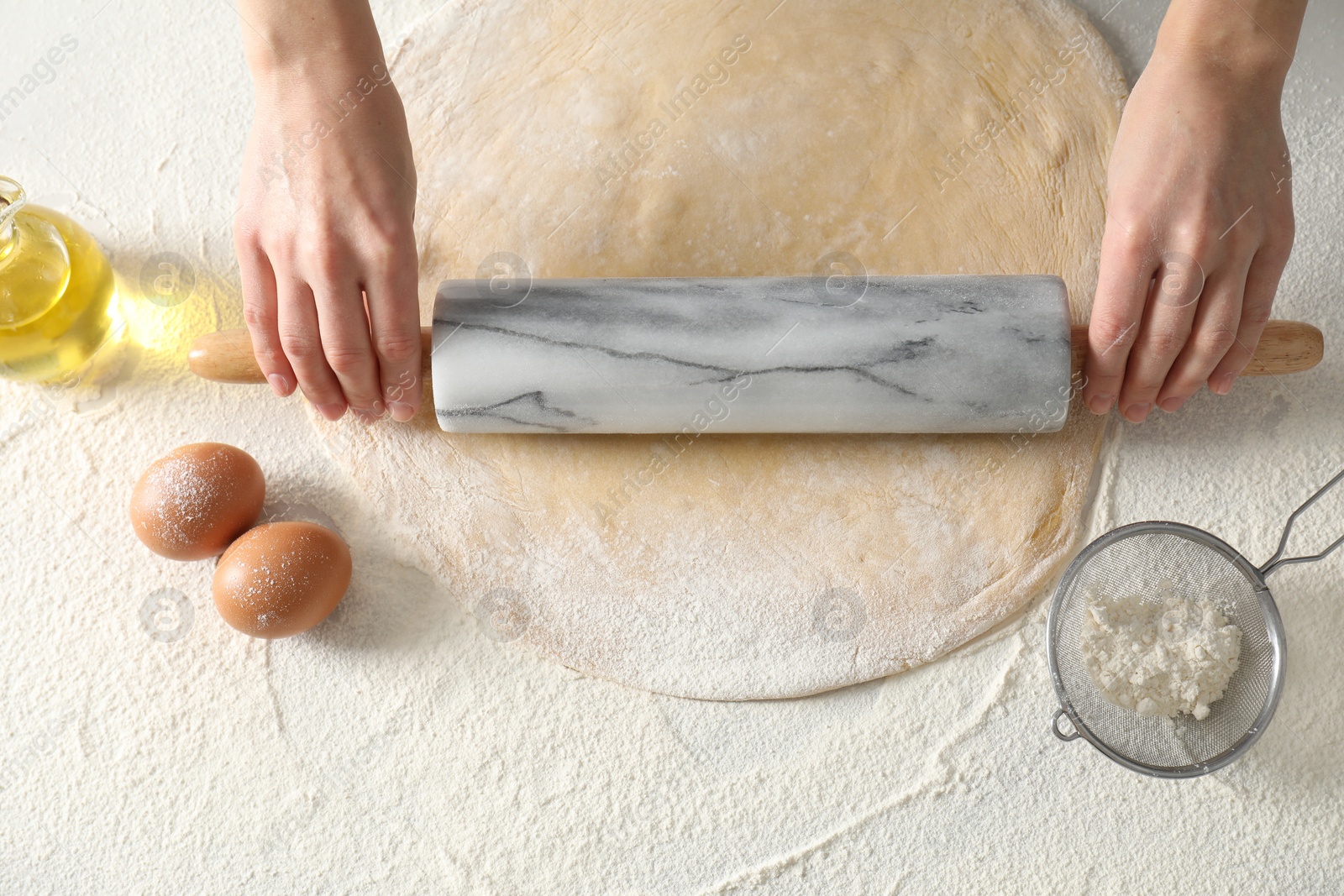 Photo of Woman rolling raw dough at table, top view