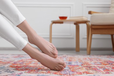 Woman on carpet with pattern at home, closeup. Space for text