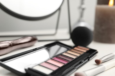 Photo of Mirror, cosmetic products and burning candle on dressing table, closeup