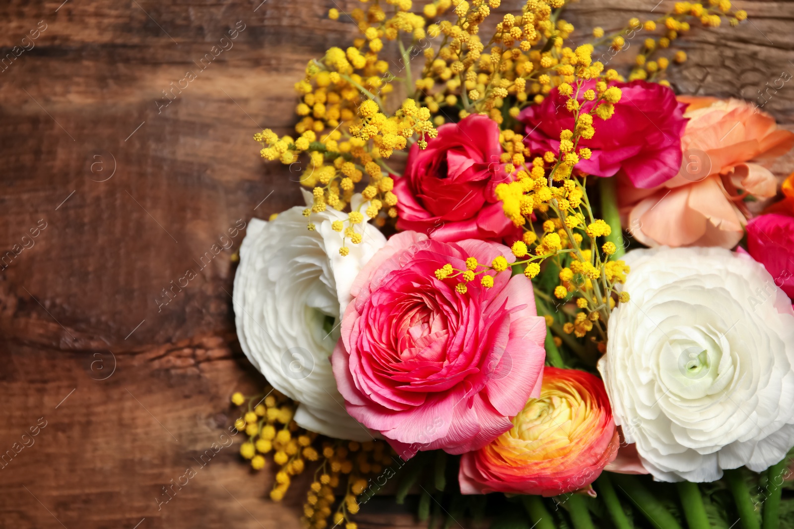 Photo of Beautiful ranunculus and mimosa flowers on wooden background