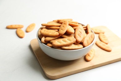 Bowl of delicious crispy crackers on white table