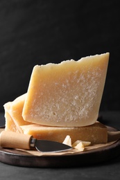 Photo of Delicious parmesan cheese with knife on black table