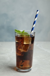 Photo of Refreshing soda drink with straw on grey table against blue background