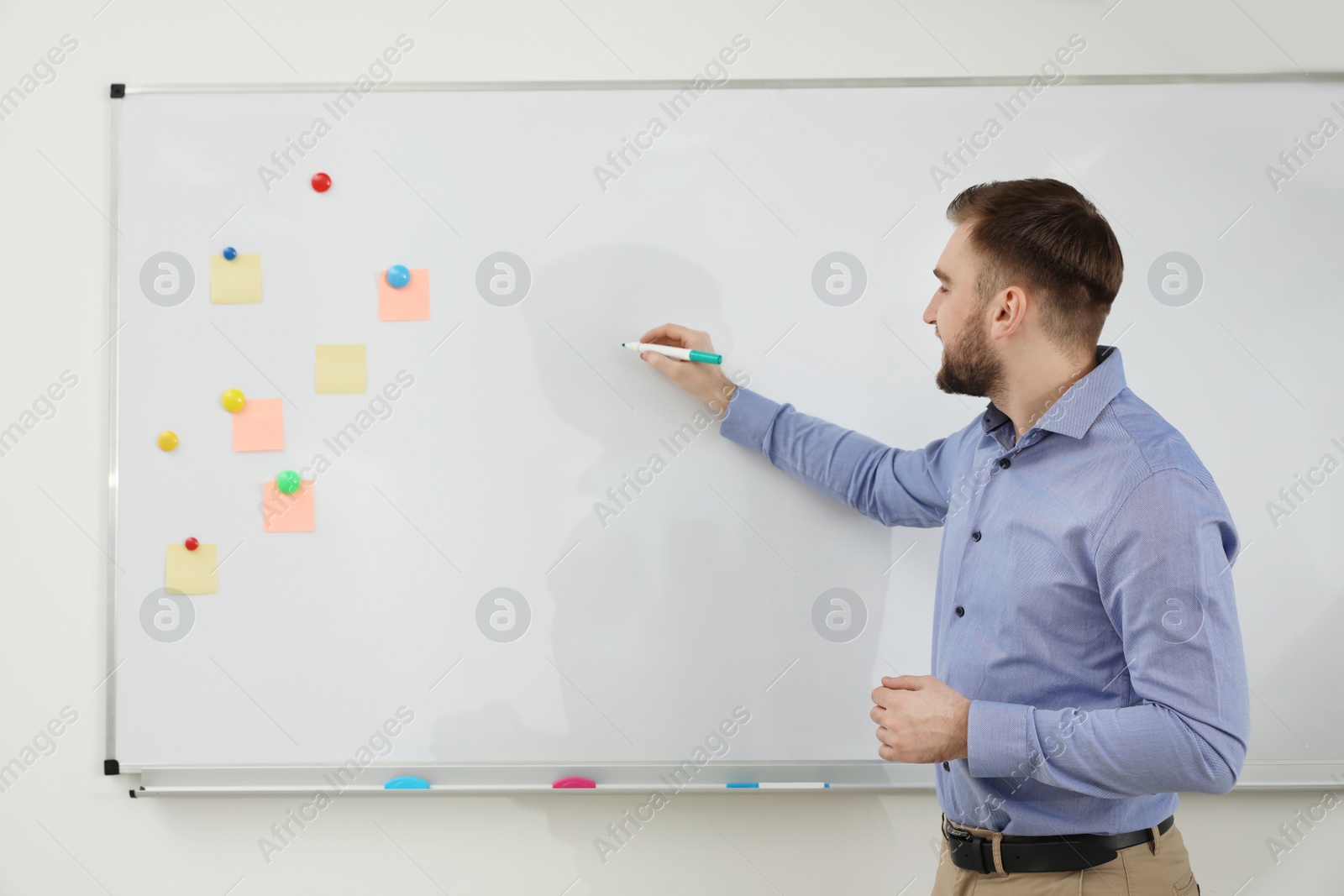 Photo of Portrait of young teacher writing on whiteboard in classroom