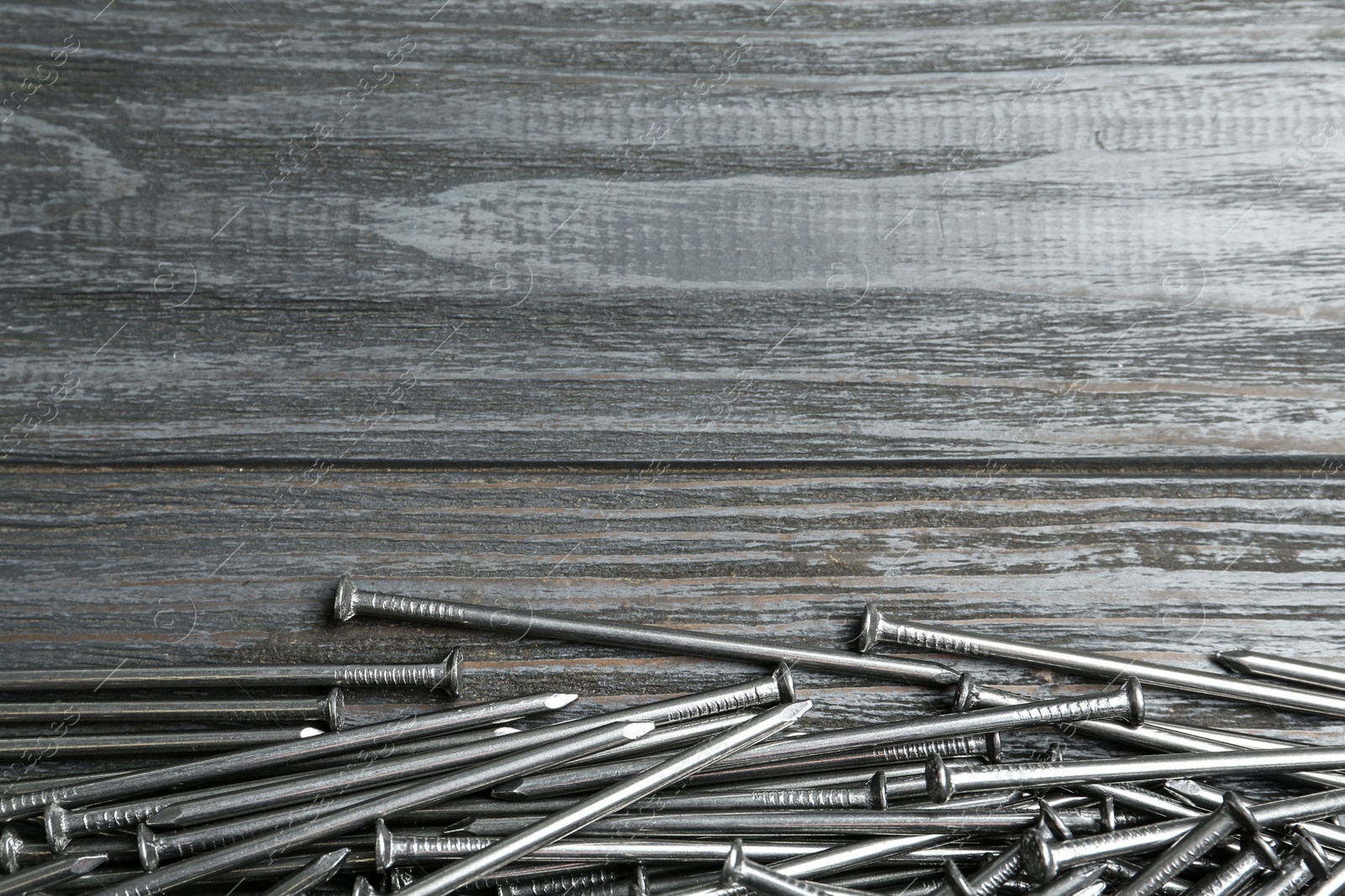 Photo of Many metal nails on wooden background, flat lay. Space for text