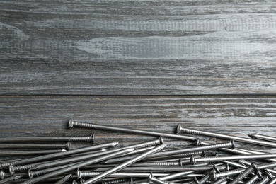 Photo of Many metal nails on wooden background, flat lay. Space for text