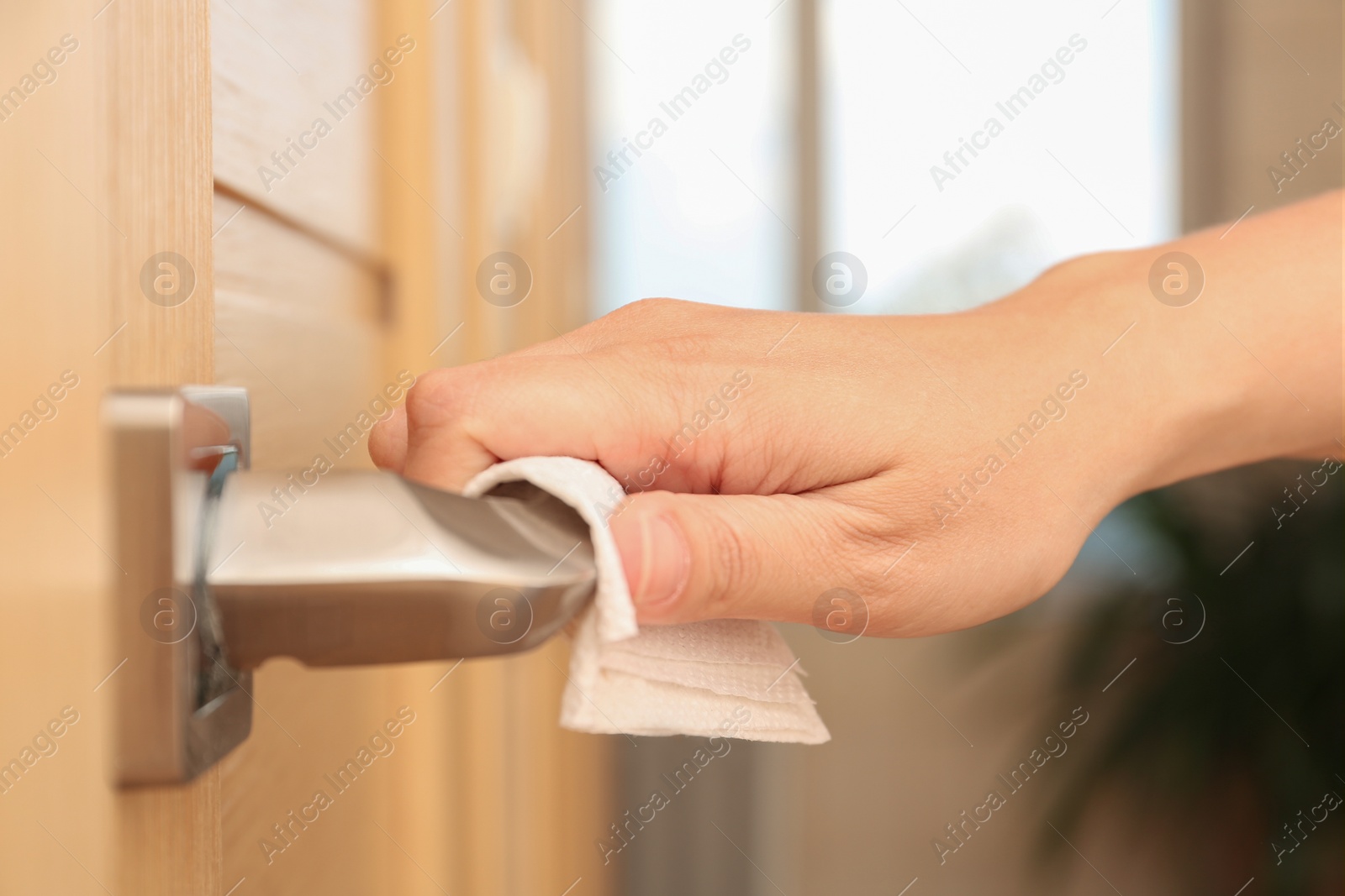 Photo of Woman using tissue paper to open door, closeup