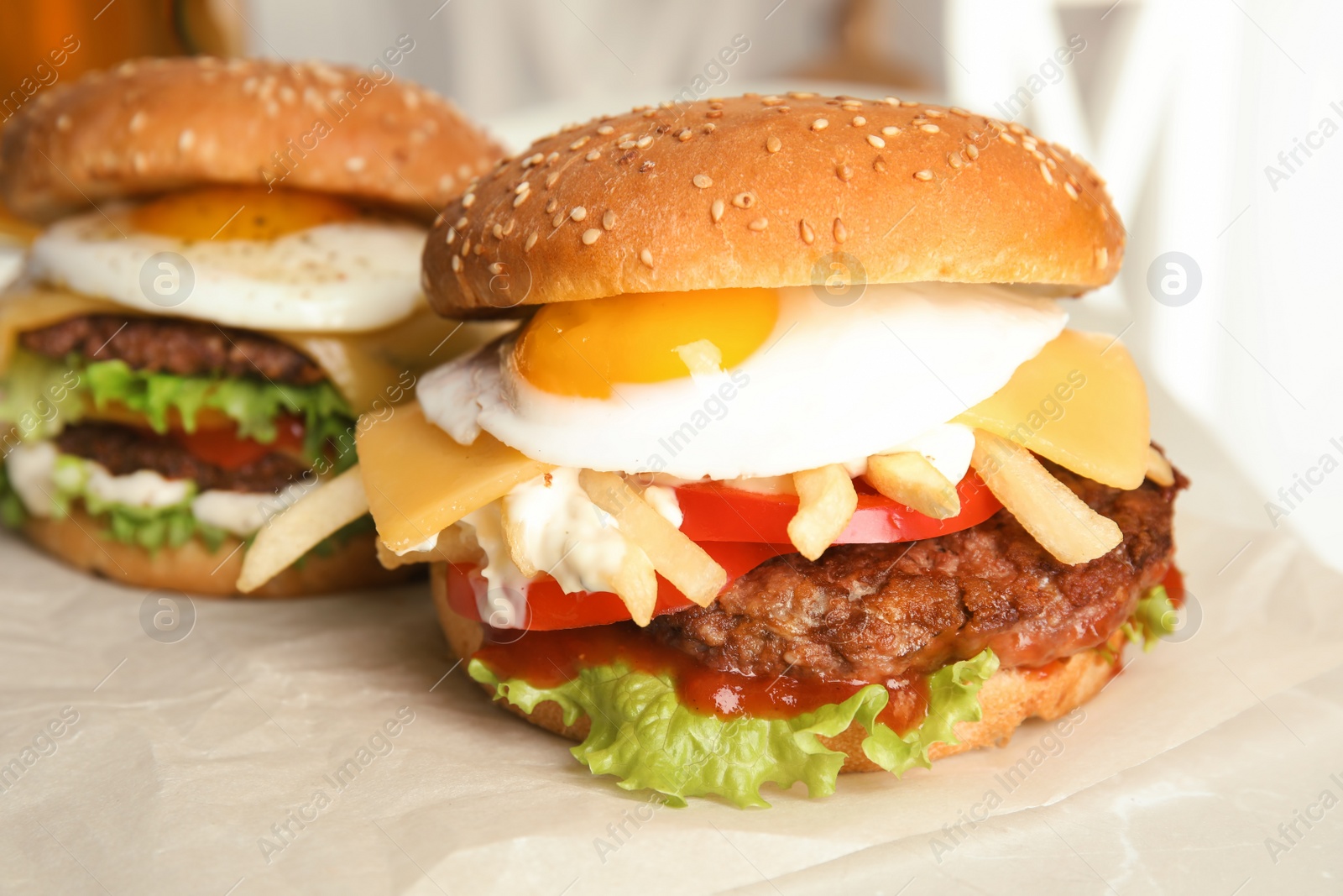 Photo of Tasty burgers with fried egg on parchment