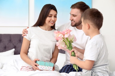 Photo of Father and son congratulating mom in bedroom. Happy Mother's Day