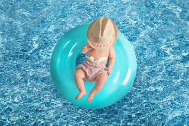 Cute little baby with inflatable ring in swimming pool, top view