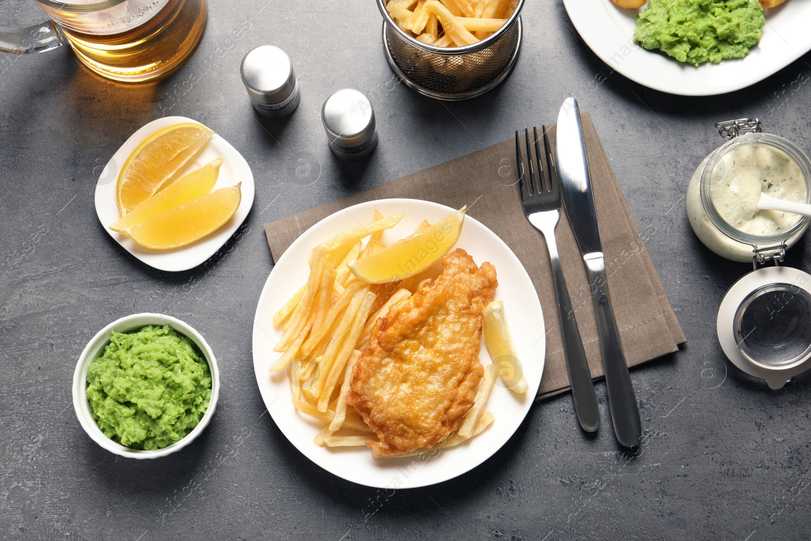 Photo of Plate with British traditional fish and potato chips on grey table, top view