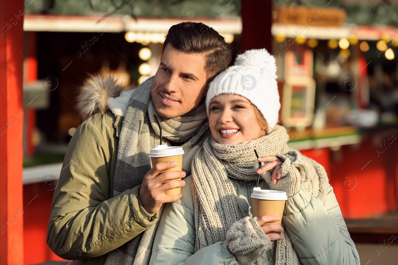 Photo of Happy couple in warm clothes with drinks at winter fair. Christmas season