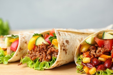 Board with delicious meat tortilla wraps on grey background, closeup