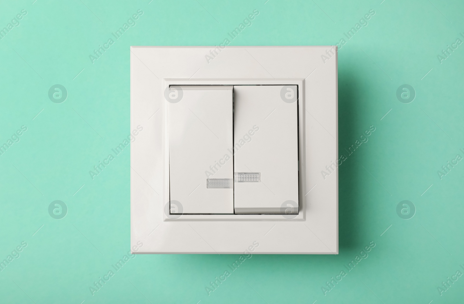 Photo of Modern plastic light switch on turquoise background