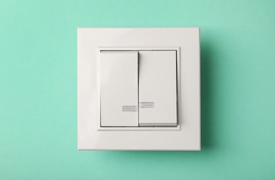 Photo of Modern plastic light switch on turquoise background