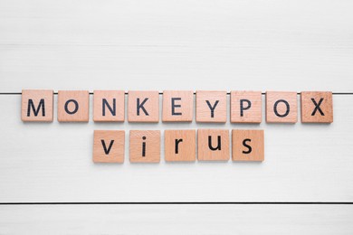 Photo of Words Monkeypox Virus made of squares on white wooden table, flat lay