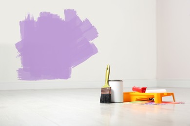 Set with decorator's tools and paint on floor near white wall