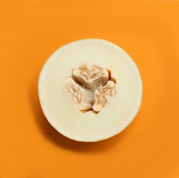 Half of ripe tasty melon on orange background, top view