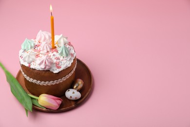 Photo of Traditional Easter cake with meringues, candle, decorated eggs and tulip on pink background. Space for text