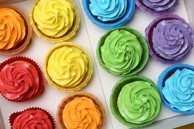 Photo of Many tasty cupcakes with colorful cream in box, top view