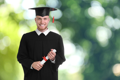 Image of Happy student with graduation hat and diploma on blurred background, space for text