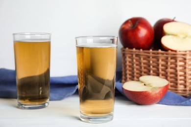Glasses of delicious apple cider on white table