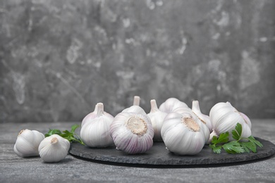 Photo of Slate plate with fresh garlic bulbs on table