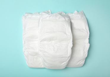 Baby diapers on turquoise background, flat lay