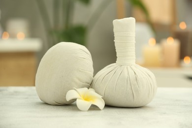 Photo of Beautiful spa composition with herbal massage bags and plumeria flower on light grey table in wellness center