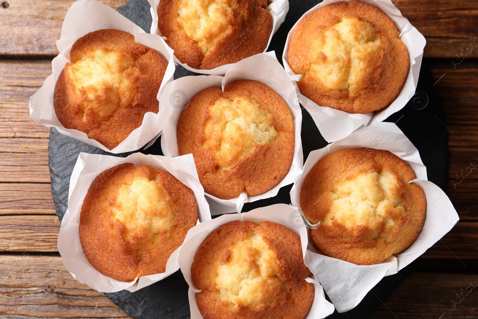 Photo of Delicious sweet muffins on wooden table, top view