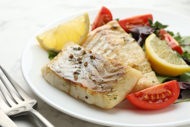 Photo of Tasty cod cooked served with salad on white table, closeup